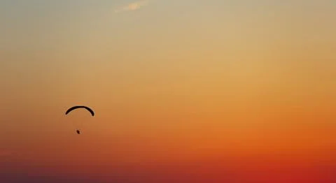 Man flight on a paraglider in a cloudless sky at sunset. Fotos de archivo