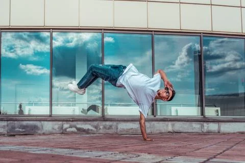 Man in flight, standing on one arm, young guy dancer, summer city, dancing Stock Photos