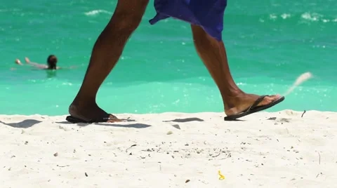 A man in flip-flops passing by on the beach. Feet close up Stock-Footage 61691692