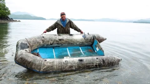 Man flipping over the boat to remove residual water Stock-Footage 83182583