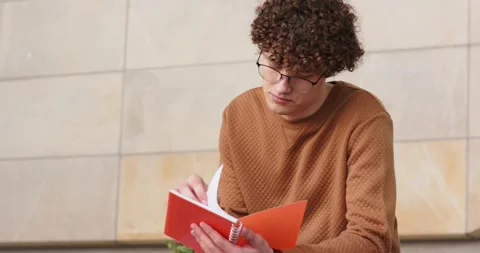 Man flipping red notebook pages to find information glancing upward focusing Stock Footage 335927573