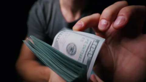Man Flipping Through Large Stack of Hundred Dollar Cash Bills in Dark Stock Footage 339366548