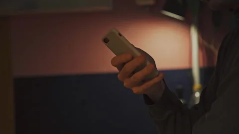 Man flipping through a tape on a smartphone screen in the kitchen in the evening Stock Footage 172575452