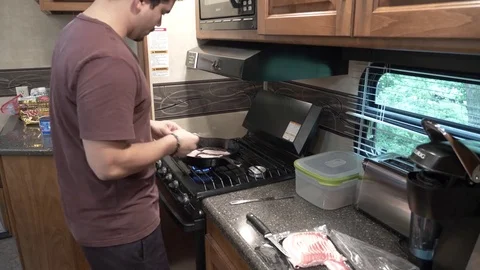 Man Flips Bacon on Gas Stove in Camper Stock Footage