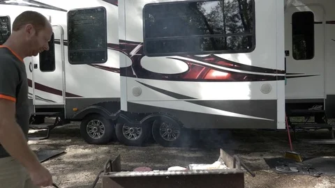 Man Flips Hamburger on Grill in Front of Toy Hauler RV Stock Footage 80539666