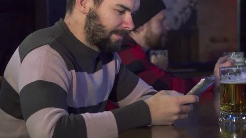 Man flips on his smartphone at the pub Stock Footage 73716771