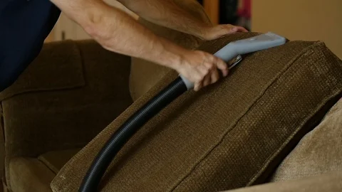 Man flips over couch cushion as he steam cleans Stock Footage 85870382