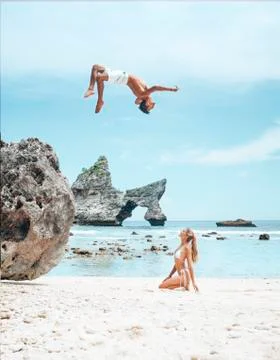 Man Flips Over Girlfriend on Beach in Nusa Penida Bali Arch Rock Stock Photos
