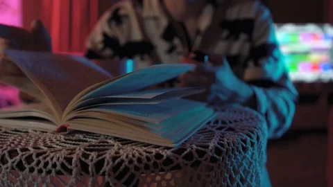 Man flips through book.He is holding a pipe and a glass of tea.cozy and warm Stock Footage 128459903
