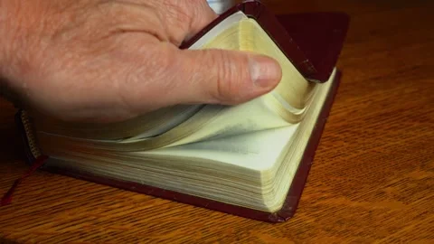 A man flips through pages of a closed Bible Stock Footage 327732547