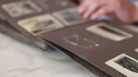 Man flips through the pages of an old album and looks through photographs. Stock Footage 148071236