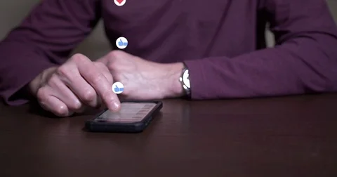 Man Flips Through Social Media as Like and Love Icons Float Up Stock Footage 75398535