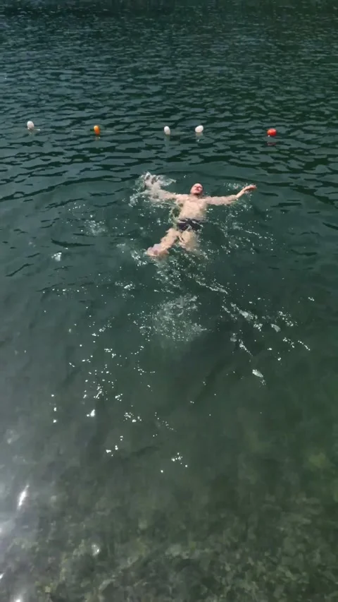 Man floating on back in mountain lake Stock Footage 160966348