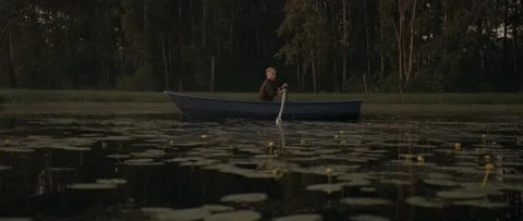 A man is floating on a boat at dawn Stock Footage 141885655