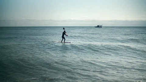 Man is floating on a surfboard, rowing with an oar. Hands of male pushing and Stock Footage 272920926