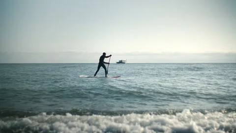 Man is floating on a surfboard, rowing with an oar. Hands of male pushing and Stock Footage 273075115