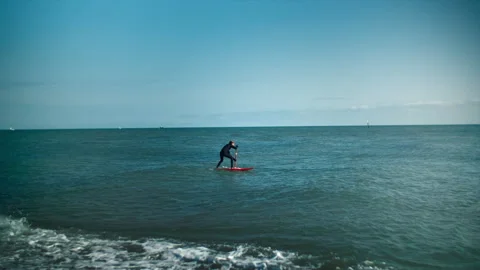 Man is floating on a surfboard, rowing with an oar. Hands of male pushing and Stock Footage 273075213