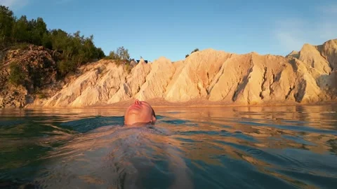 A man floats on his back towards a picturesque beach. Stock Footage 251463717