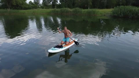 A man floats on a sup board along the surface of the lake. Stock-Footage 246291007
