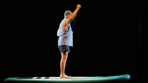 A man floats on a sup board on a black background while standing 库存影片 219643728