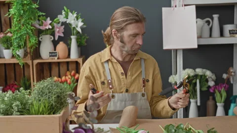 Man florist in studio holds pruning shears and inspects blades at a workben.. Stock Footage 339193387