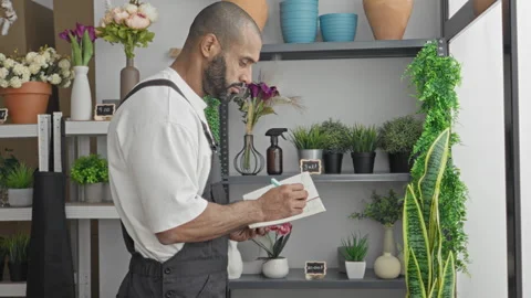 Man florist writes in notebook with bare hand while checking plant stock in.. Stock Footage 337373729
