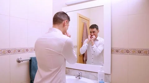 Man flossing teeth in front of bathroom mirror Stock Footage 312308206