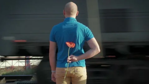 A man with flower waiting for a passing train Stock Footage 97946341