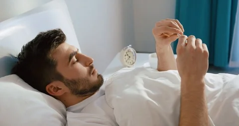 Man with flu is suffering from headache and checking his body temperature on the Stock Footage 93452771