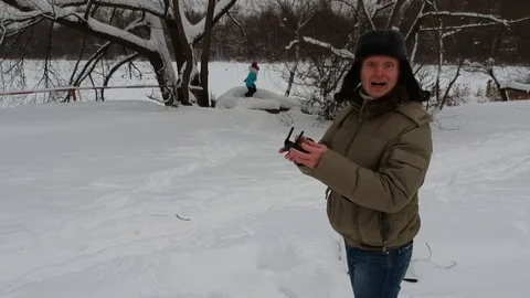Man fly drone from remote control panel and take kidding crazy selfie winter Stock Footage 101789618