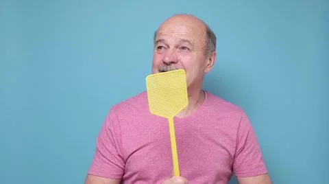 Man with fly swatter trying to kill mosquito on blue background. Stock Photos