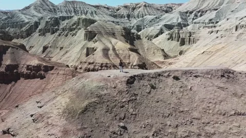 Man flying drone over eroded badlands with striated rock in Altyn Emel Stock Footage 345410174
