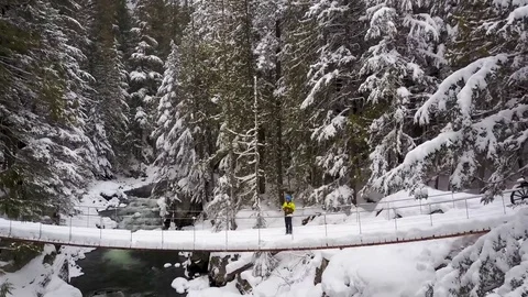 Man Flying Drone In A In A Snow Forest Over A River Video stock 78076102