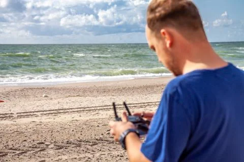 Man flying his drone by using a remote controller on the beach Stock Photos