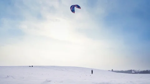A man with flying parachute is doing snow kiting, then falling in the snow Stock Footage 88096902