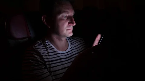 Man is flying by the plane at night. he look at something in his phone, in the Stock Footage 97189601