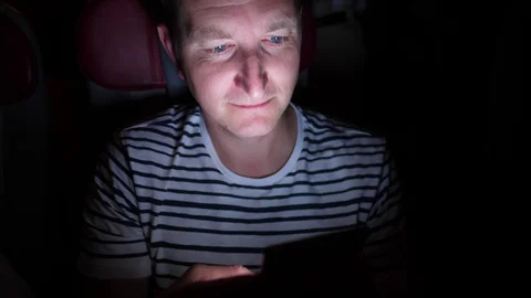 Man is flying by the plane at night. he browsing in his phone in the dark Stock Footage 97189810