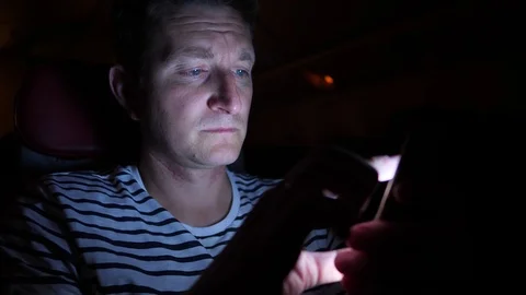Man is flying by the plane at night. he zooming something in his phone in the Stock Footage 97192772