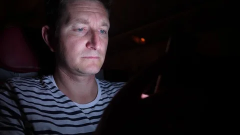Man is flying by the plane at night. he reads something in his phone in the dark Stock Footage 97193331