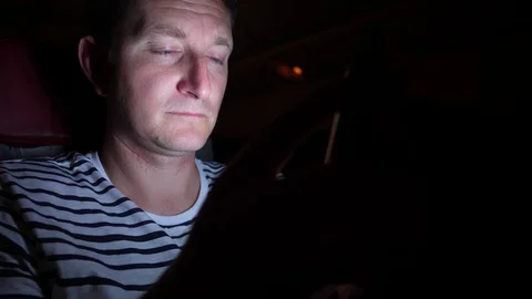 Man is flying by the plane at night. he reads something in his phone in the dark Stock Footage 97193792