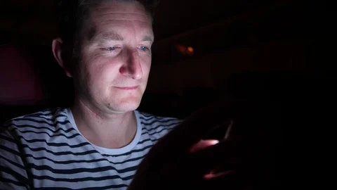 Man is flying by the plane at night. he reads something in his phone in the dark Stock Footage 97193993