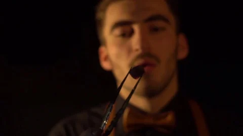 Man in the focus blows on the piece of the hookah coal. The close-up view of the Stock Footage 79676507