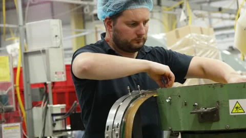 Man focused on assembling parts at a workstation, cap lining machine in a Stock Footage 274054336