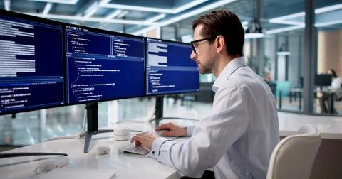 Man Focused On Coding Software At Desk In Quiet Office Space. Stock Photos
