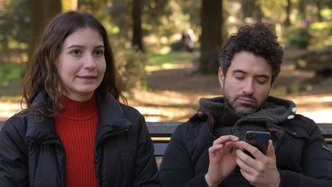 Man focused on his cell not listening to  his girlfriend talking to him-outdoor Stock Footage 118599101
