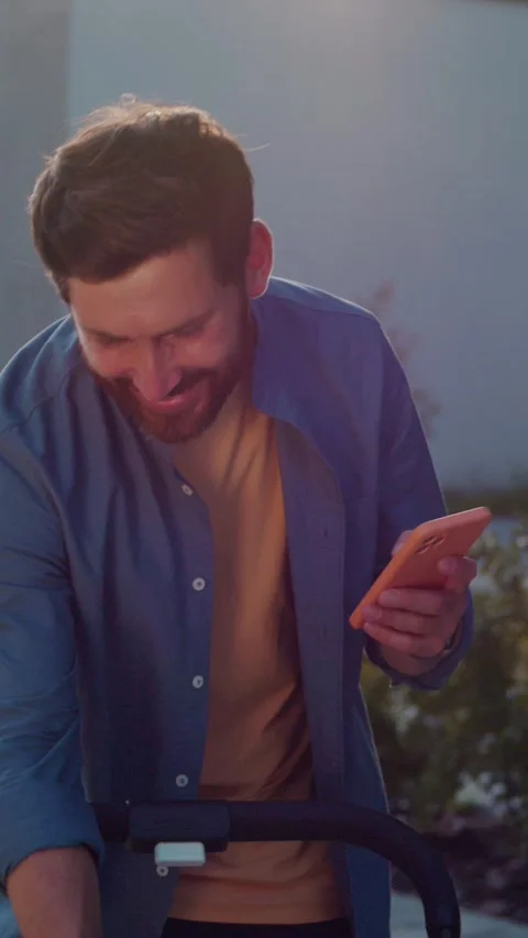 A man is focused on his smartphone, absorbed in a vibrant outdoor environment Stock Footage 314364118