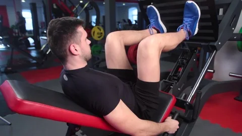Man focused on training legs on the machine in the gym Stock Footage 73230787