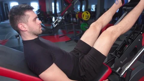 Man focused on training legs on the machine in the gym Stock Footage 73230816