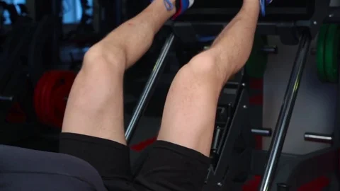 Man focused on training legs on the machine in the gym Stock Footage 73230948