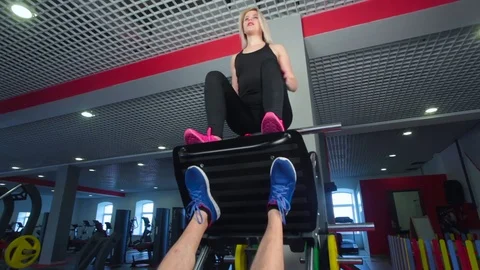 Man focused on training legs on the machine in the gym with trainer Vídeo Stock 73231046
